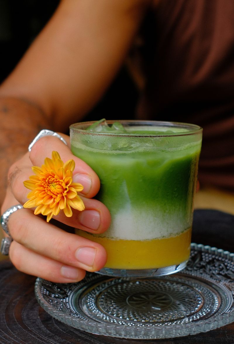Iced matcha held in a hand with an orange blossom at Nenek